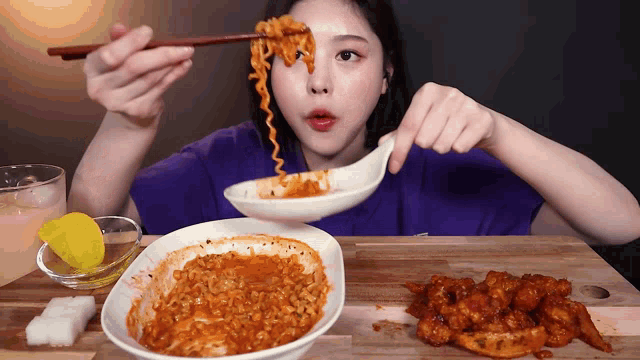 a woman eating noodles with chopsticks and a spoon