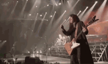 a man is playing a guitar on a stage in front of a microphone .