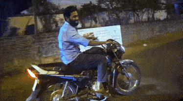 a man riding a motorcycle with a sign behind him that says t.
