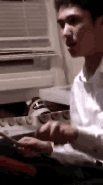 a man in a white shirt is playing a guitar