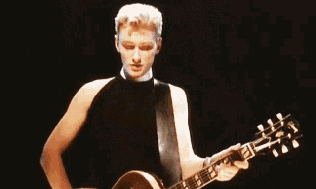 a man is playing a gibson guitar in a black tank top