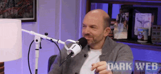 a bald man is sitting in front of a microphone with the words dark web written on the bottom .