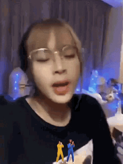 a woman wearing glasses and a black shirt is making a funny face .