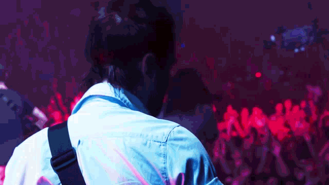 a man playing a guitar in front of a crowd with red lights