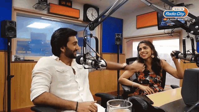 a man and a woman are in front of microphones in a radio station called radio city