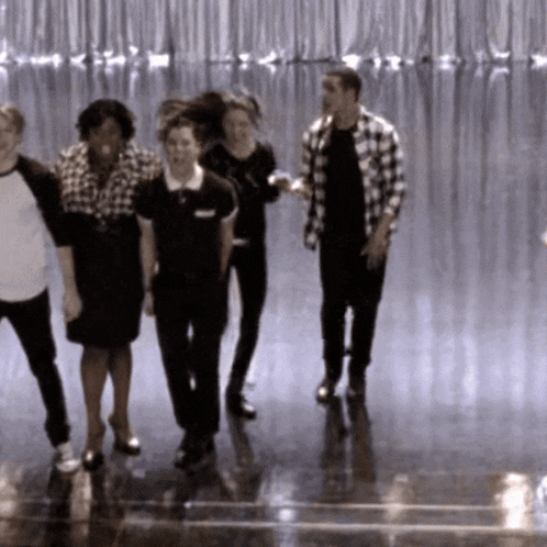 a group of people standing on a stage with a man wearing a plaid shirt