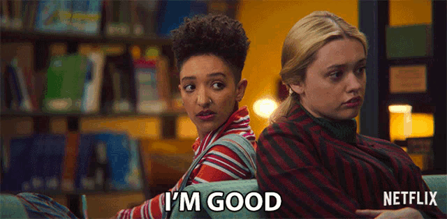 two girls are sitting back to back and one of them is saying i 'm good ..