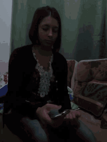 a woman is sitting on a couch looking at her cell phone