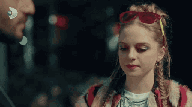 a woman wearing red sunglasses and a braided hairstyle