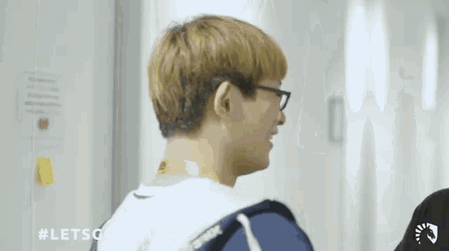 a man wearing glasses is standing in a hallway .