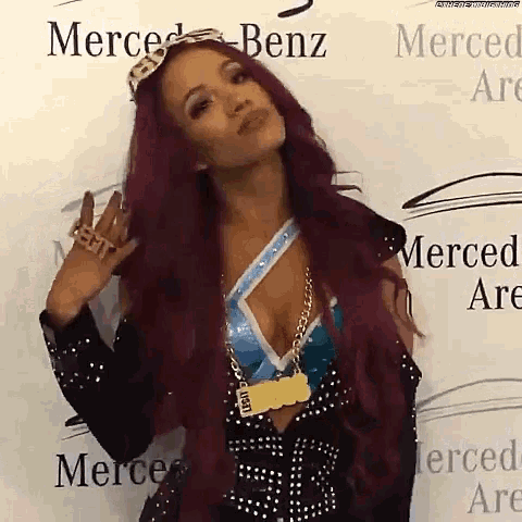 a woman with long red hair is standing in front of a wall that says merced benz .