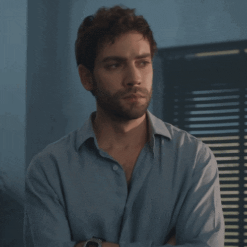 a man with his arms crossed is wearing a blue shirt