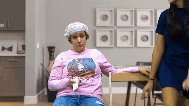 a woman wearing a pink sweater that says " i 'm a frog " holds a remote control