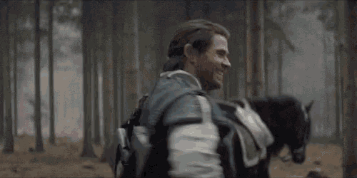 a man is riding a horse in the woods and smiling .