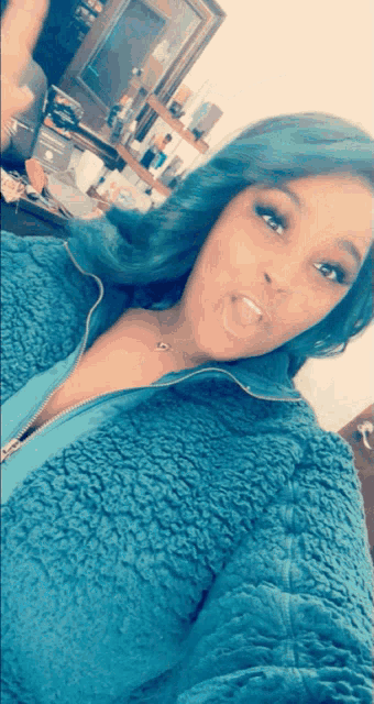 a woman with blue hair is taking a picture of herself