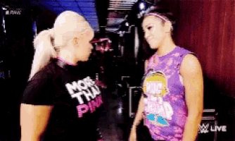 a couple of women are standing next to each other and one of them is wearing a shirt that says more than pink .