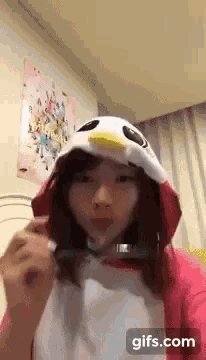 a woman is wearing a penguin costume and holding a pair of glasses .