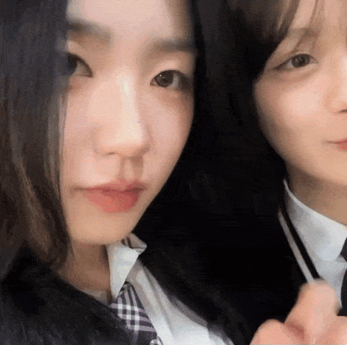two girls in school uniforms are posing for a photo