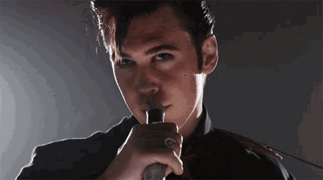 a man with a ring on his finger holds a microphone in his hand