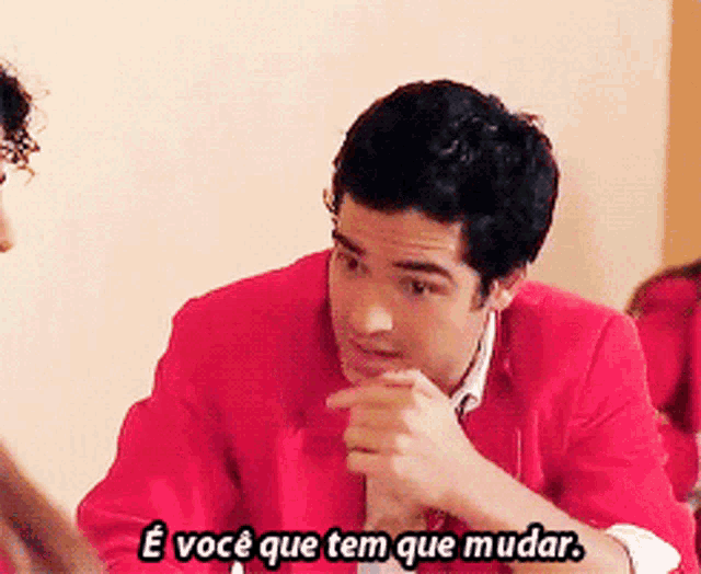 a man in a red jacket says " e você que tem que mudar " while talking to another man