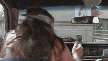 a woman is sitting in the driver 's seat of a car looking at her phone