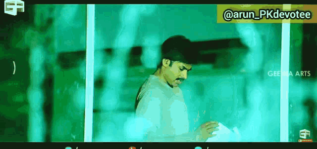 a man in a white shirt is standing in front of a window with a green background ..