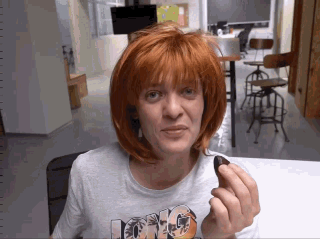 a woman wearing a long t-shirt holds a small object