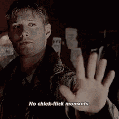 a man is making a stop gesture with his hand and says `` no chick flick moments '' .