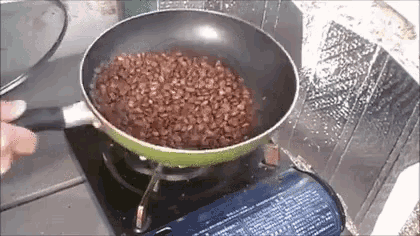 a frying pan filled with brown beans is cooking on a stove .