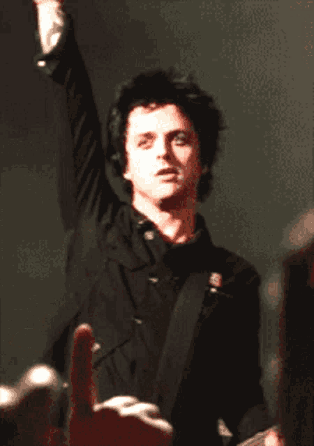 a man in a black shirt is playing a guitar with his arm in the air