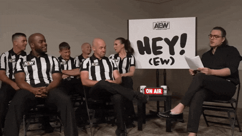 a group of referees are sitting around a sign that says hey