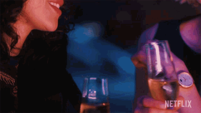a man holding a glass of champagne next to a woman with a netflix logo