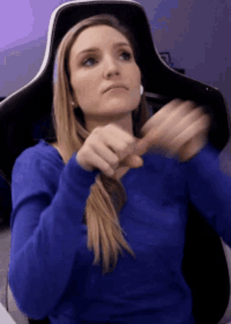 a woman wearing a blue sweater is sitting in a gaming chair