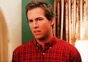 a man in a red plaid shirt is standing in a room .