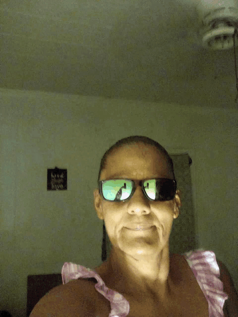 a woman wearing sunglasses is taking a selfie in front of a sign that says " life is good "