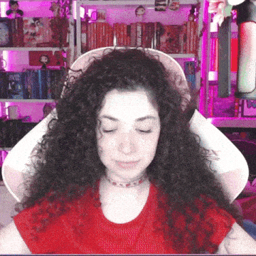 a woman with curly hair is sitting in front of a bookshelf that has a book called i 'm not a fan