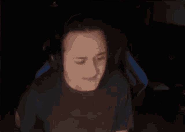a man wearing headphones is sitting in a chair with his mouth open in the dark .