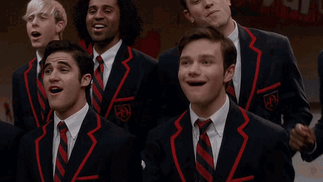 a group of men in suits and ties with a red stripe on the sleeves