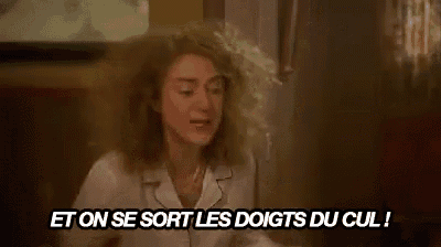 a woman with curly hair is sitting at a table with a knife in her hand and talking in a foreign language .