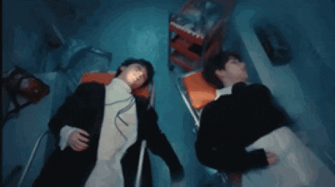 two men are laying in a hospital bed with their heads down .