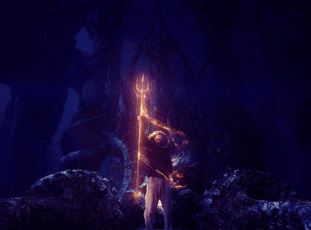 a man with a beard is holding a trident in a dark room