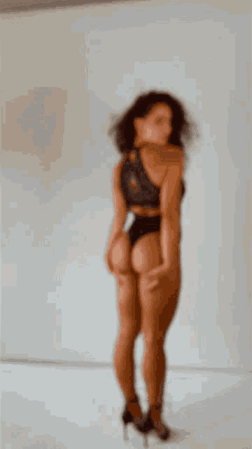 a woman in a black lace bodysuit is standing with her hands on her butt