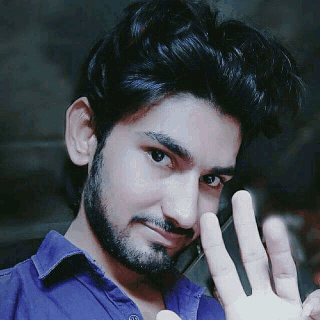 a man with a beard wearing a purple shirt is holding up his hand