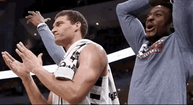 two basketball players are clapping their hands and one has a shirt that says basketball on it