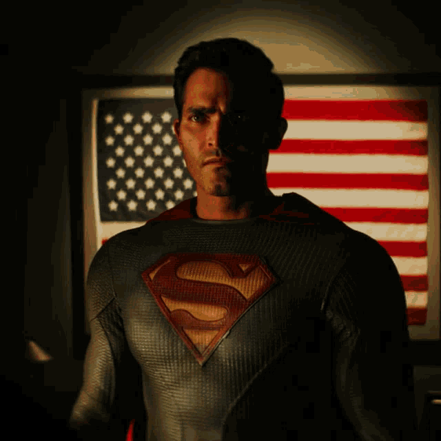 a man in a superman costume stands in front of a flag