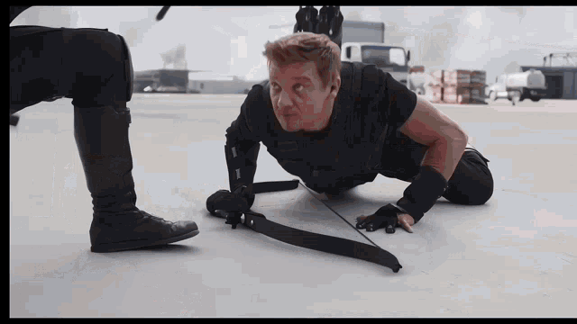 a man laying on the ground with a bow and arrow in his hand