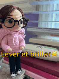 a crocheted doll wearing glasses and a pink sweater with lever et briller written below it