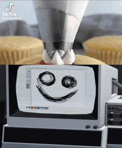 a drawing of a smiley face on a computer screen next to a cupcake