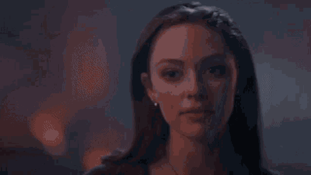 a close up of a woman 's face looking at another woman in a dark room .