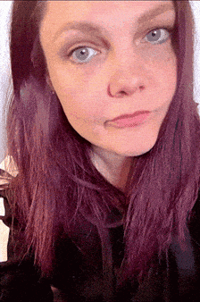 a woman with purple hair is making a funny face